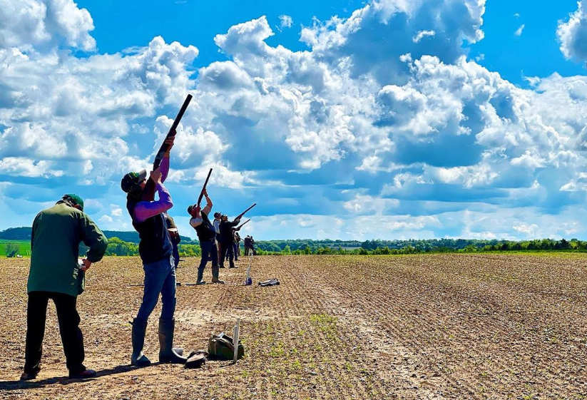 People lined up in a row at a clay pigeon shoot