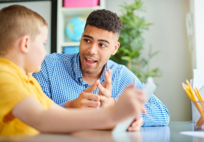 male teacher talking to small boy 